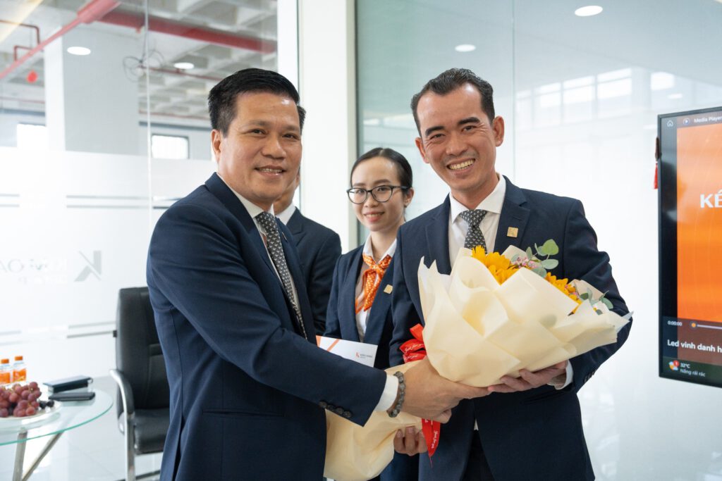 Anh Trần Trọng Minh Hoàng – Giám đốc Chi nhánh Dĩ An (bên phải) nhận bó hoa chúc mừng từ ông Tô Duy Chinh – Giám đốc Khối Kinh doanh Tập đoàn